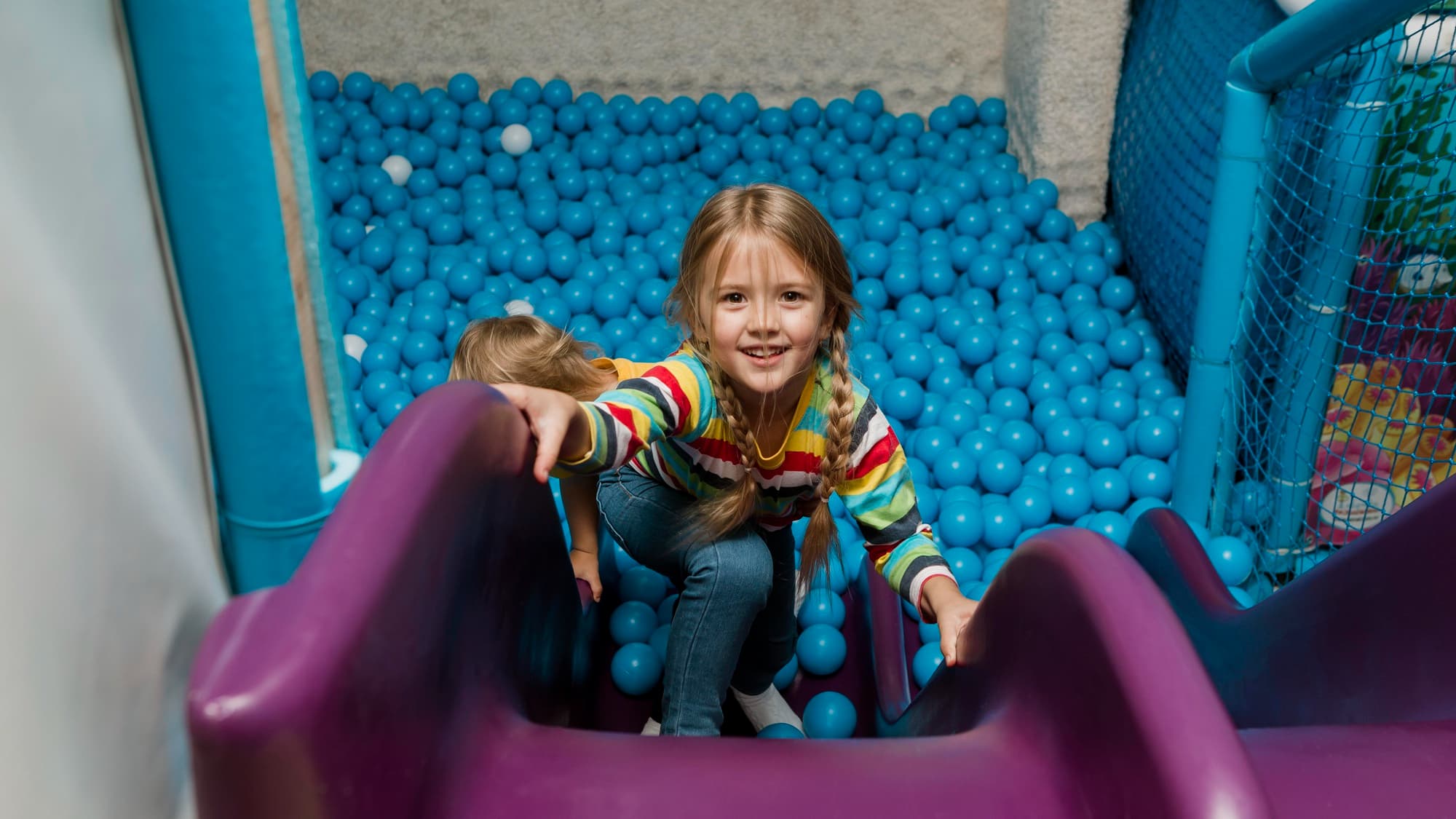 Niña jugando en alberca de pelotas